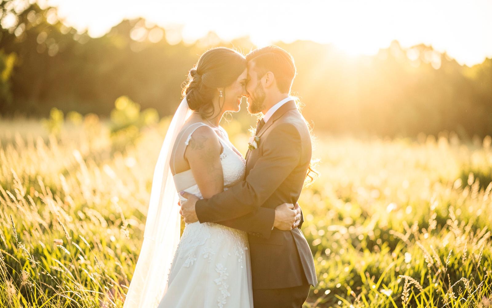 Bride and groom embracing in a golden sunlit meadow